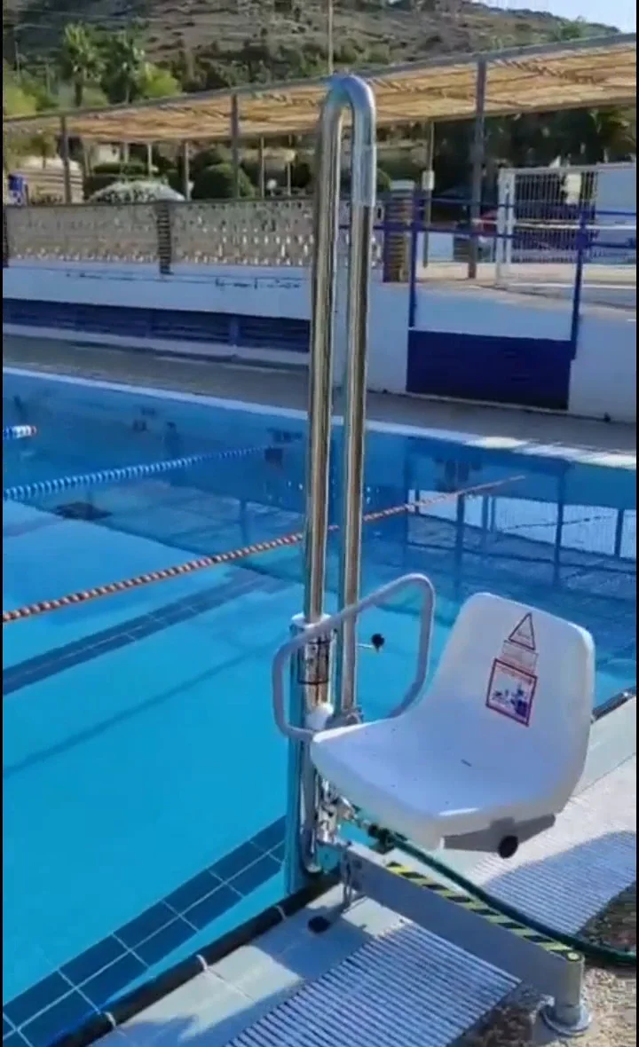 Ascensor acuático hidráulico de acero inoxidable con su silla, instalado en el borde de una piscina